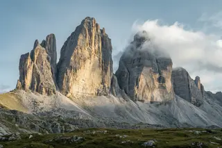 Two Dolomite towers side by side, one lit and one in cloud.