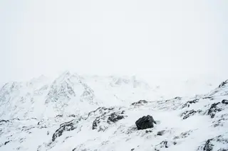 A tiny dark rock and a faint ridge in a blizzard of white on white.